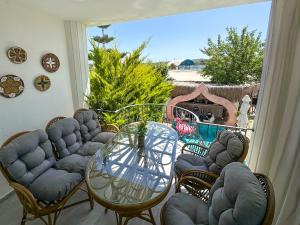 patio con mesa de cristal y sillas en el balcón en NURİYE ALACATI, en Alacati
