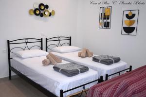 two beds in a room with white walls at Casa di Pino in Paradisi Square near Airport in Paradeísion