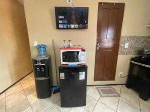 a kitchen with a microwave on top of two trash cans at Residence Fonteles in Sobral