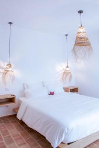 a bedroom with a white bed with two pendant lights at Mar-Ria 4 in Fuzeta