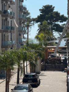 two cars parked in a parking lot with palm trees at Rei Apartments in Shëngjin