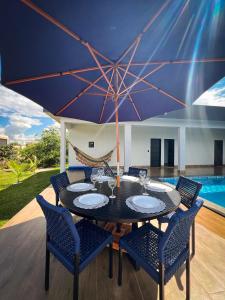 a table with chairs and a large umbrella at Casa Frente ao Lago com Piscina Aquecida no Melhor Condomínio in Abadiânia