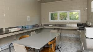 a kitchen with a large white table and chairs at Waitangi Holiday Park in Paihia