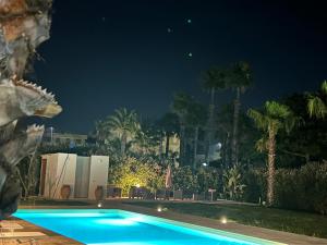 a swimming pool at night with palm trees at B&B Brezza Delle Egadi in Marsala