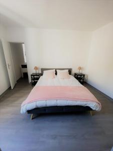 a large bed in a white room with two tables at 2 pièces élégant calme central parking sur place in Foix