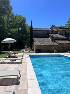 a swimming pool with two lounge chairs and an umbrella at Le Moulin de Montségur in Montségur-sur-Lauzon