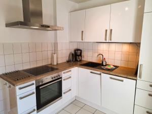 a kitchen with white cabinets and a stove top oven at Chalet an der Bode - Schicke 3 Zi Fewo mit Balkon in Braunlage
