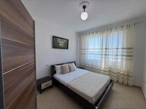 a bedroom with a bed and a large window at SunKissed Apartament in Golem