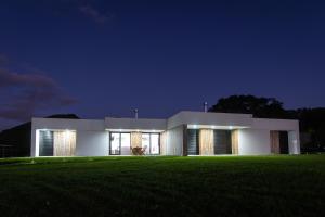 圣维森特费雷拉Vila Vicente Jacuzzi, Sauna and Parking的夜晚的白色大楼和绿色田野