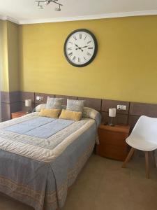 sypialnia z dużym łóżkiem z zegarem na ścianie w obiekcie Marina d'Or, apartamentos Valparaíso w mieście Oropesa del Mar