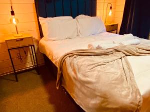 a bed with white sheets and pillows in a room at Sherwood Castle by Liv Retreats in Nottingham