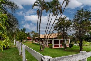 a white fence in front of a house with palm trees at Villa do Haras in Espirito Santo Do Pinhal