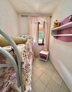 a small bedroom with a bed and a window at Appartamento Rosè in San Teodoro +5 photos