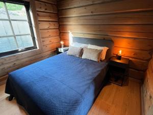 a bedroom with a blue bed in a wooden cabin at Exclusive Fjord Lodge with Private Jacuzzi and Epic Views in Lii