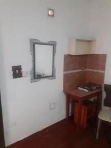 Un espejo en una pared al lado de una mesa con un espejo. en Departamento Monoambiente, en La Rioja