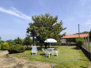 a table and chairs and an umbrella in a yard at Casa Sindo in Teixeira
