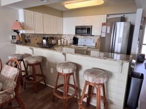 a kitchen with a counter with stools and a refrigerator at Sunrise Pointe 11F Condo in Myrtle Beach