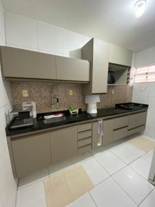 a kitchen with white cabinets and black counter tops at Casa Completa SJ - 6KM in Campina Grande