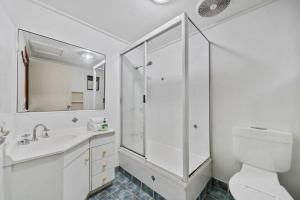 a white bathroom with a shower and a toilet at Billa Blue by Discover Stradbroke in Point Lookout +9 photos