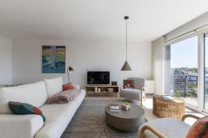 ein Wohnzimmer mit einem weißen Sofa und einem Fernseher in der Unterkunft Arian 0401 in Saint-Idesbald