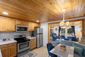 a kitchen and living room with wooden ceilings and a table at Cozy Cottages Green Cottage Hot tub-Town in Saugatuck