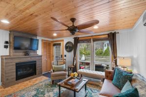 a living room with a ceiling fan and a fireplace at Cozy Cottages Red Cottage Hot tubTown in Saugatuck