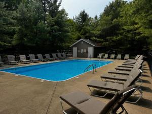 une piscine avec chaises longues et transats dans l'établissement The Timber Nest Goshorn lake dock pool town, à Saugatuck