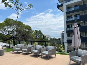 a patio with chairs and an umbrella and a building at Lindo Studio Aconchegante no Ingá in Niterói