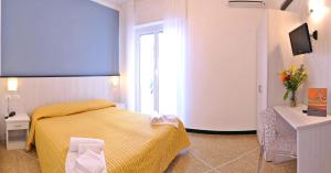 a bedroom with a yellow bed and a television at Hotel Bristol in Laigueglia