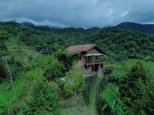 una casa sul fianco di una collina con alberi di Master bed room in Bukit Cottage a Noca