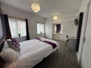 a bedroom with a large white bed and two windows at Oldbury House - Bespoke for Contractors in Smethwick