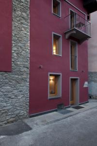 a red building with a balcony on the side of it at Guesthouse Mu in Aosta