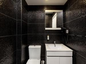 a black tiled bathroom with a toilet and a sink at Feel Porto Wine Essence IV in Vila Nova de Gaia +32 photos