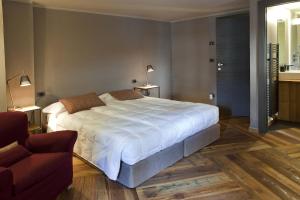 - une chambre avec un grand lit blanc et une chaise dans l'établissement Guesthouse Mu, à Aoste