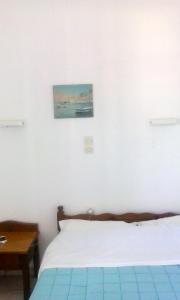 a bedroom with a bed and a table and a painting at Vaso Rooms in Livadakia