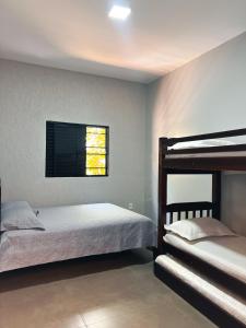a bedroom with two bunk beds and a window at Casa Frente ao Lago com Piscina Aquecida no Melhor Condomínio in Abadiânia