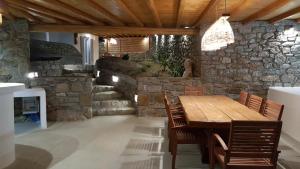 a dining room with a wooden table and a stone wall at Otherview Villa in Super Paradise Beach