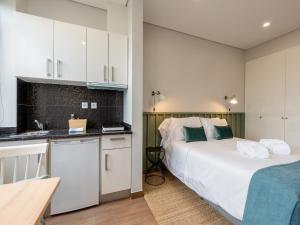 a bedroom with a bed and a kitchen with white cabinets at Feel Porto Wine Essence II in Vila Nova de Gaia
