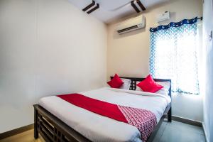 SecunderābādHotel O Grand Brundavan的一间卧室，有一张带红色枕头的床和一扇窗户