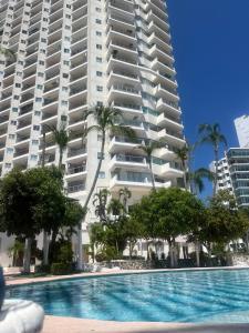 a swimming pool in front of a large apartment building at La Palapa Acapulco in Acapulco