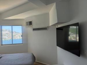 a bedroom with a bed and a tv on the wall at La Palapa Acapulco in Acapulco