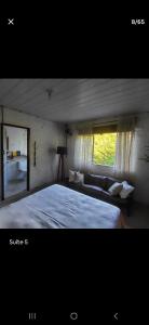 a bedroom with a bed and a couch and a window at Casa Darwin in Maricá
