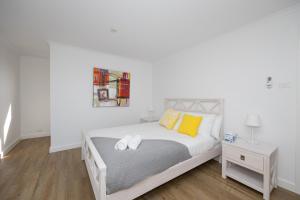 una camera da letto bianca con un letto con cuscini gialli di Ocean View Cottage - Anglesea a Anglesea