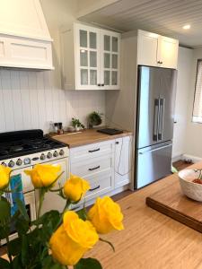 una cucina con mobili bianchi e fiori gialli di Country Cottage Charm a Mittagong