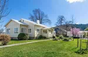 una casa bianca con un prato davanti di Country Cottage Charm a Mittagong