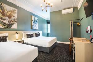 PymbleNightcap at Pymble Hotel的有两张床和一张书桌的酒店房间