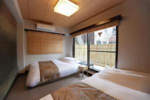 Un dormitorio con dos camas y una gran ventana. en Asakusa Premium Stay 彩-Irodori-, en Tokio