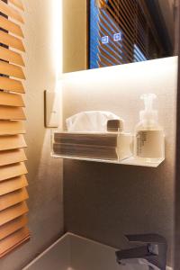 un lavabo con una botella de jabón y un espejo en Asakusa Premium Stay 彩-Irodori-, en Tokio