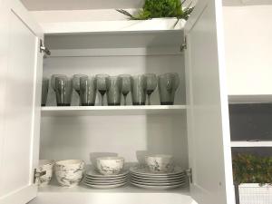 a cupboard with plates and glasses in it at NEW! 2 minutes from Convention Center, Palms Crossing Shopping & South Texas College in McAllen
