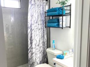 a bathroom with a toilet and a shower with blue towels at NEW! 2 minutes from Convention Center, Palms Crossing Shopping & South Texas College in McAllen